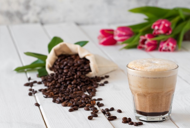 Cappuccino in a glass on a white wooden table