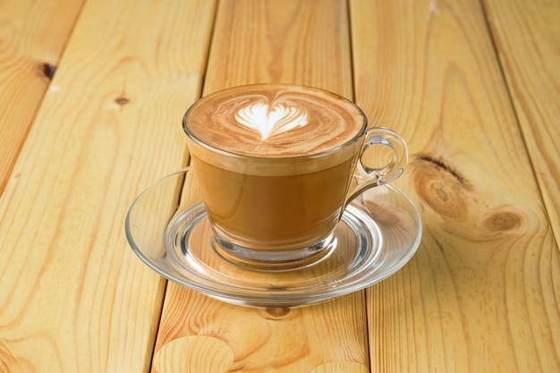 Cappuccino in transparante glazen beker op houten tafel