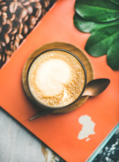 Cappuccino-koffie in glas boven tafel met tijdschriftachtergrond