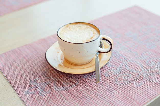 Cappuccino-koffie met latte art bovenop in beige keramische mok Warme koffie met amandelmelk in een coffeeshop Veganistische plantaardige melk voor ontbijt Heerlijke en stijlvolle cappuccino