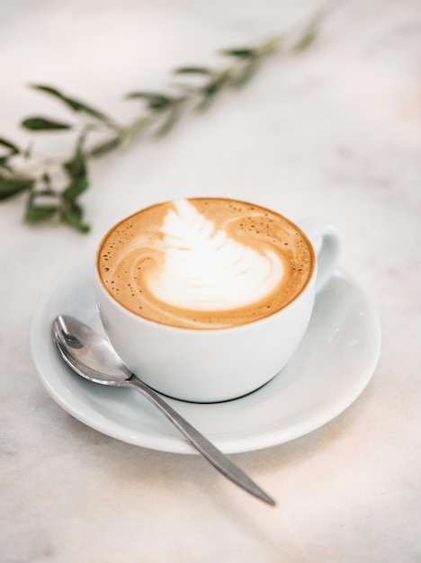 Cappuccino-koffiedrank in witte kop met latte art-top