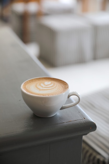 コーヒーショップの木製テーブルに牛乳から作られたカプチーノまたはラテアートコーヒー