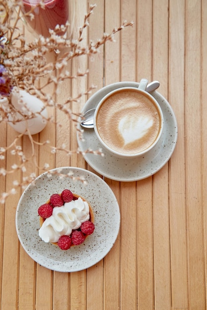 Cappuccino roze frambozen smoothie dessert franse suikervrije taart tussen decoratieve bloemen