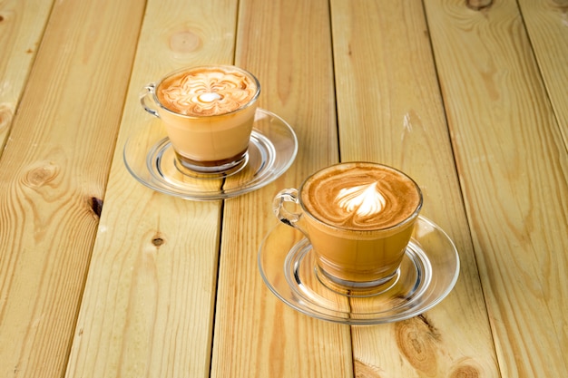 Cappuccino in transparent glass cup on wooden table