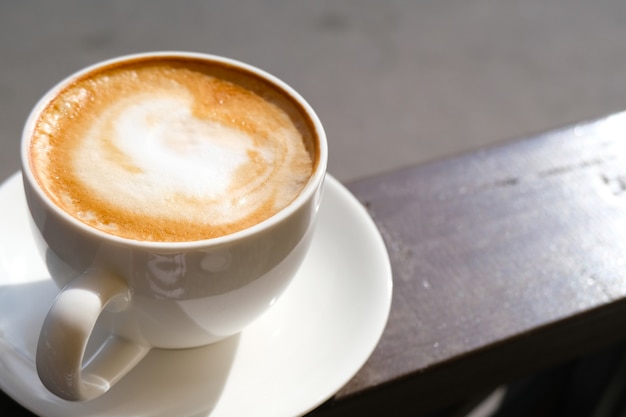 Cappuccino in white cup on sunlight at cafe