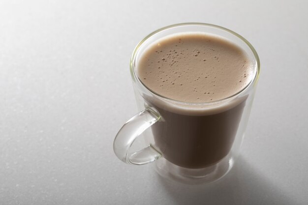 Cappuccino with chocolate on a white marble style in a transparent glass cup.