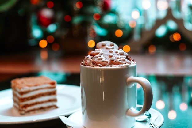 Cappuccino with gingerbread man and honey cake on the background of Christmas lights