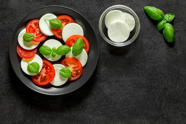 Caprese Italiaanse antipasto met mozzarella basilicum en tomaten op donkere achtergrond bovenaanzicht ruimte om tekst te kopiëren