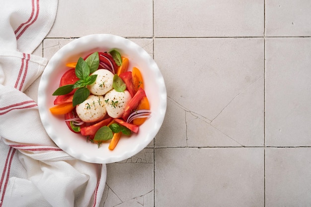 Салат капрезе Итальянский салат капрезе с нарезанными помидорами, сыром моцарелла, базиликом, оливковым маслом в белой тарелке на белом фоне Вкусная итальянская еда Вид сверху Деревенский стиль