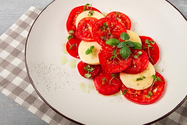 Caprese salad Italian traditional dish tomatoes with mozzarella cheese basil and spices top view no people