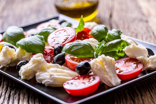 Caprese Salad Mozzarella cherry tomatoes basil and olive oil on old oak table Italian cuisine