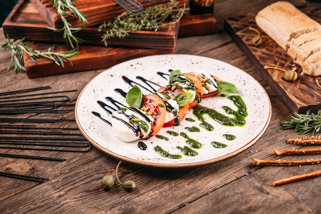 Caprese salad with pesto sauce on the wooden table
