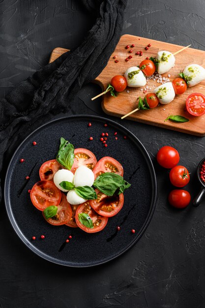 Caprese salad with tomato and mozzarella slices with basil leaves