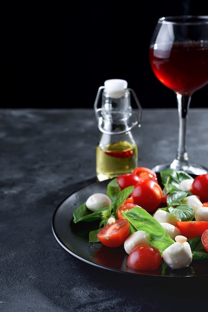 Caprese salade. Gezonde maaltijd met cherrytomaatjes, mozzarella ballen en basilicum met rode wijn