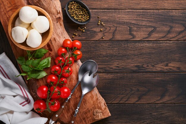 Caprese salade ingrediënten voor het koken snijden houten plank met traditionele caprese voorbereiding ingridients mozzarella tomaten basilicum olijfolie kaas kruiden op houten rustieke achtergrond