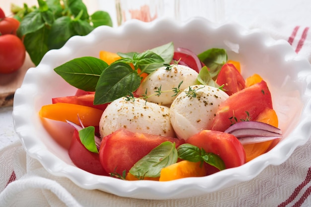 Caprese salade Italiaanse caprese salade met gesneden tomaten mozzarella kaas basilicum olijfolie in witte plaat op witte achtergrond heerlijk Italiaans eten bovenaanzicht rustieke stijl