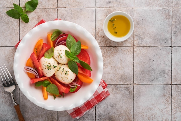 Caprese salade Italiaanse caprese salade met gesneden tomaten mozzarella kaas basilicum olijfolie in witte plaat op witte achtergrond heerlijk Italiaans eten bovenaanzicht rustieke stijl