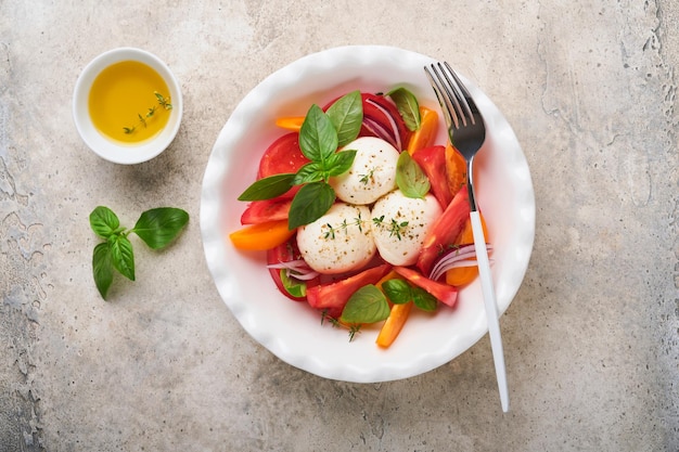 Caprese salade Italiaanse caprese salade met gesneden tomaten mozzarella kaas basilicum olijfolie in witte plaat op witte achtergrond heerlijk Italiaans eten bovenaanzicht rustieke stijl