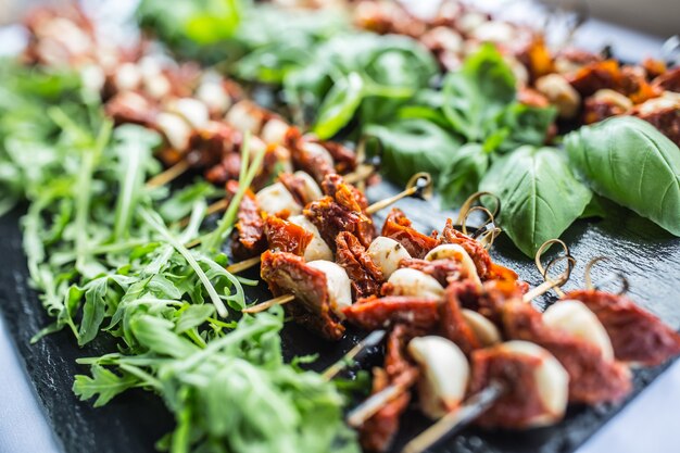 Foto caprese salade met gedroogde tomaten mozzarella basilicum en rucola op leisteen bord.