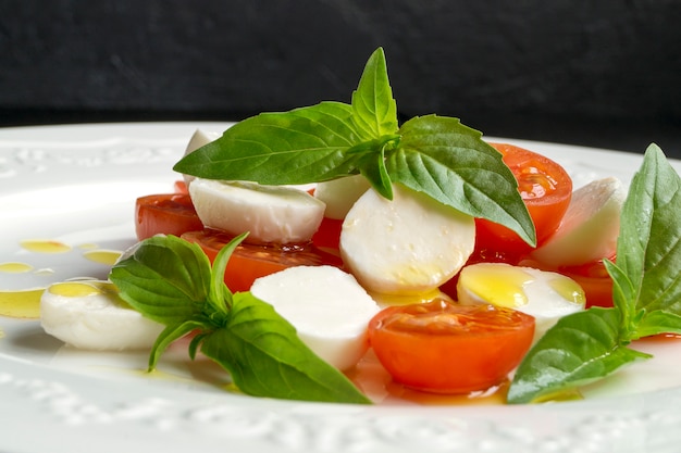 Caprese salade met rijpe tomaten en mozzarella met verse basilicumblaadjes. Italiaans eten.