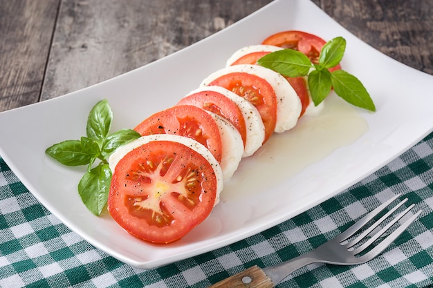 Capresesalade met de tomaten van de mozarellakaas en basilicum op rustieke houten lijst