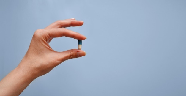 capsule in hand on a blue background medication medical workers day medical care banner for the hospital
