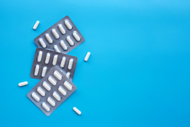 Capsule medicines in blister pack on blue background.