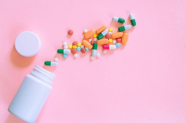 Capsule pill spread out from white plastic pill bottle on pink background Pharmacy banner Online