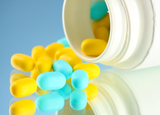 Capsules in bottle on blue background