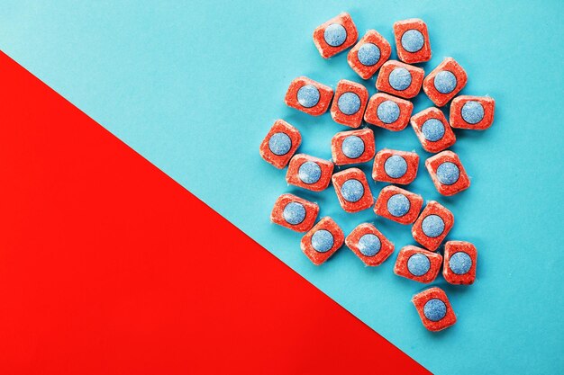 Capsules for kitchen dishwashers on a blue and red background flat lay