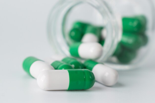 Capsules lie next to a glass jar