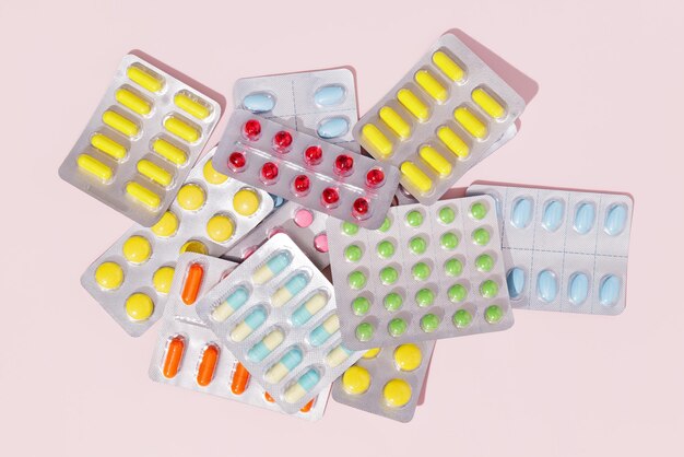 Capsules and pills packed in blisters on a pink background