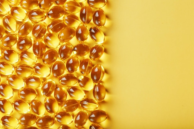 Capsules in a shell with liquid vitamin D3 on a yellow background and a place for text