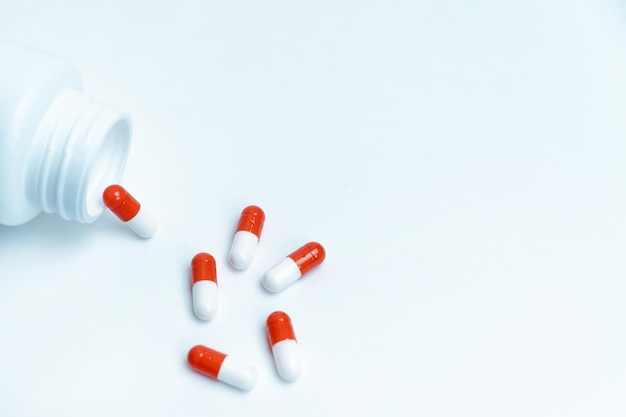 Capsules with medicine and an empty bottle on a white background