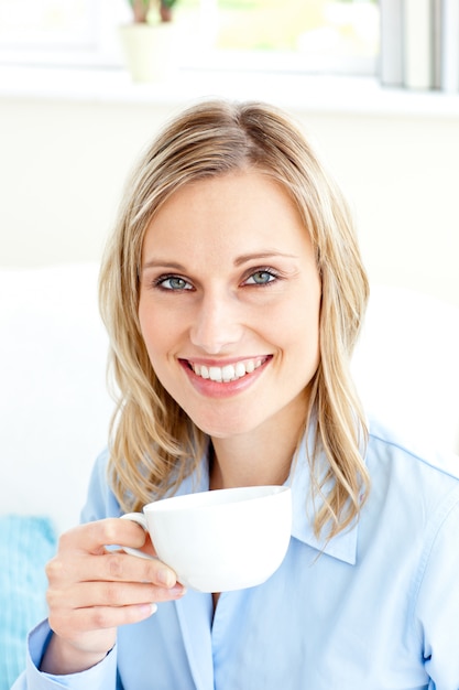 Captivating businesswoman holding a cup sitting on a sofa