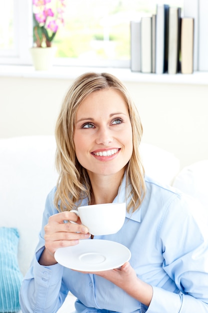 Captivating businesswoman holding a cup sitting on a sofa