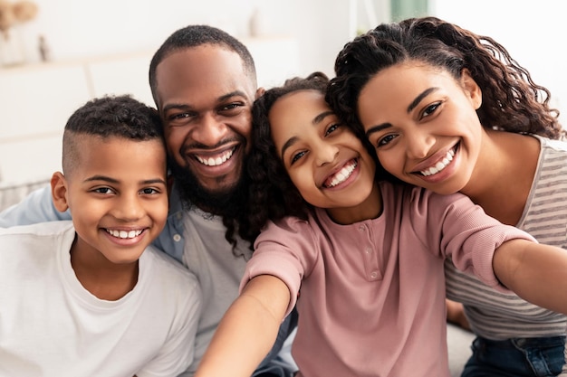 Catturare momenti. ritratto di felice famiglia nera amorevole di quattro persone che prendono selfie insieme, primo piano. genitori positivi che posano con i loro bambini e sorridono, ragazza che tiene la macchina fotografica, pov