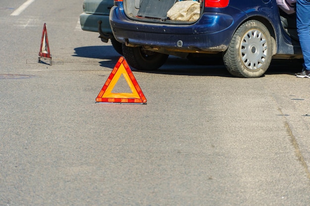 Car accident A brokendown passenger car is on the road after an accident Road sign of an emergency stop Accident insurance on the road