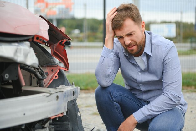 Foto incidente d'auto uomo dopo incidente d'auto l'uomo si rammarica dei danni causati durante l'incidente d'automobile