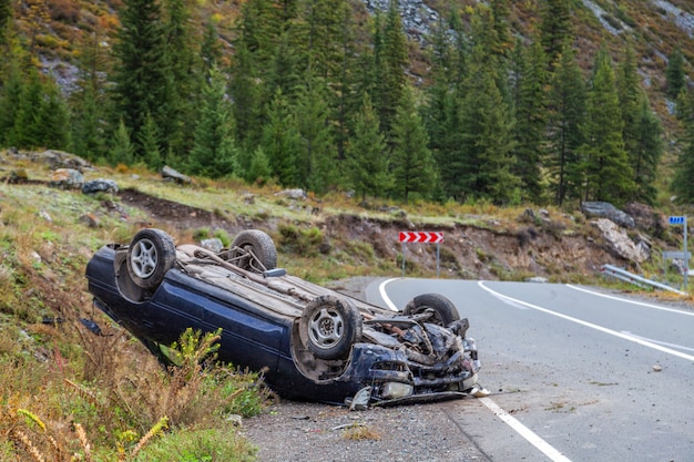 Car accident place on a bend, overturned car lies on the roof,