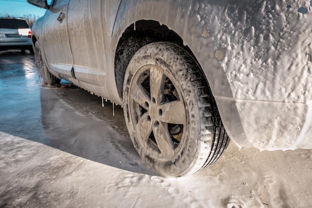 Car in active foam on car washing. Industrial transportation theme