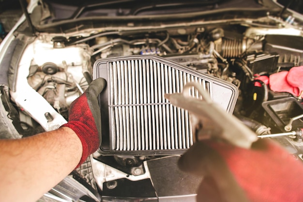 Car air filter in auto mechanic hand is blowing dust and cleaning with air blow gun