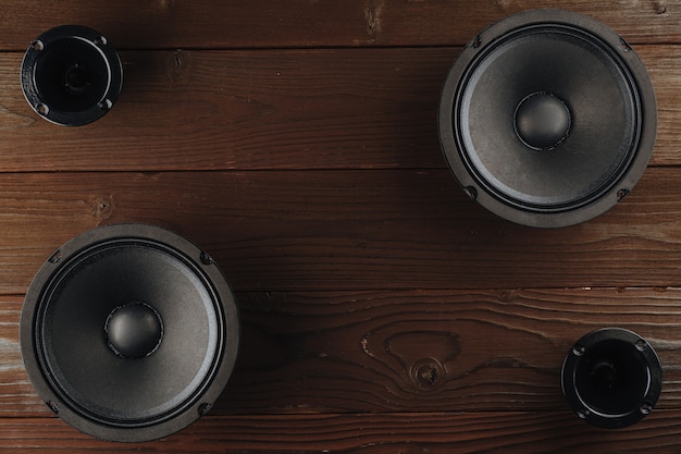 Car audio black car speakers lie on a brown wooden background