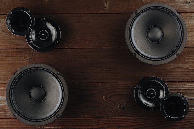 Car audio, black car speakers lie on a brown wooden surface.