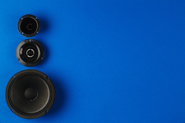 Car audio car speakers bass speaker and midrange speaker lie in a row on a blue background