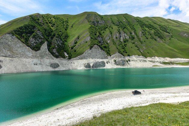 A car on the background of Lake Kezenoyam in the Caucasus mountains in Chechnya Russia June 2021