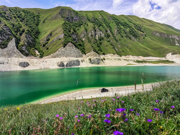 A car on the background of Lake Kezenoyam in the Caucasus mountains in Chechnya Russia June 2021