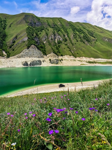 A car on the background of Lake Kezenoyam in the Caucasus mountains in Chechnya Russia June 2021