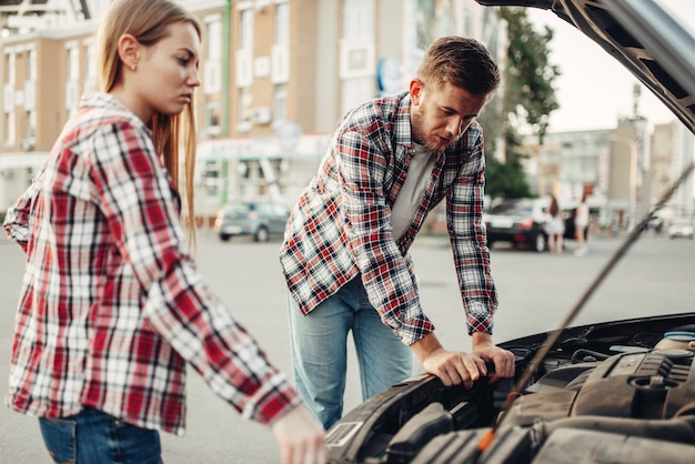 Concetto di ripartizione auto, coppia contro il cofano aperto