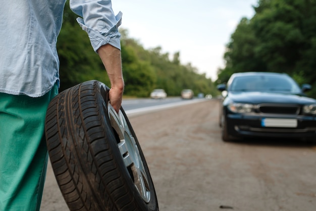 Car breakdown, man puts the spare tyre.